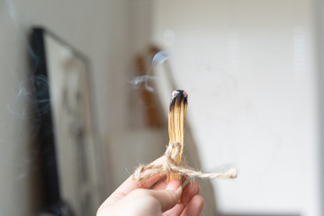 Rytuał palenia patyka aromaterapia. Kobieca dłoń trzyma palo santo. Pali w mieszkaniu kadzidło. 