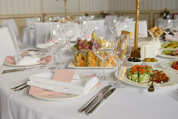 Table setting with blank guest card, white plate with pink serviette and cutlery on table, copy space. Place setting at wedding reception. Table served for wedding banquet in restaurant