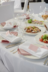 Table setting with blank guest card, white plate with pink napkin and cutlery on table, copy space. Place setting at wedding reception. Table served for wedding banquet in restaurant