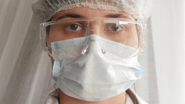 doctor in protective mask and protective goggles looking at camera, portrait