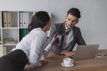 sexy secretary touching tie of handsome businessman while seducing him in office