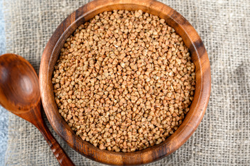 Buckwheats in a wood bowl on a sack cloth and light background.