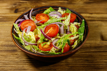 Healthy salad with savoy cabbage, cherry tomato, red onion and olive oil on wooden table