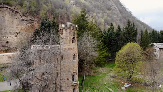 Aerial flying around the old abandoned castle-like building. Filmed in the mountains of the Caucasus. Aerial shot taken by drone in spring