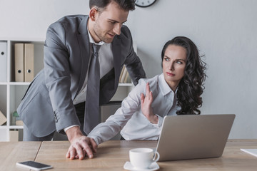 angry secretary showing stop gesture to businessman touching her hand