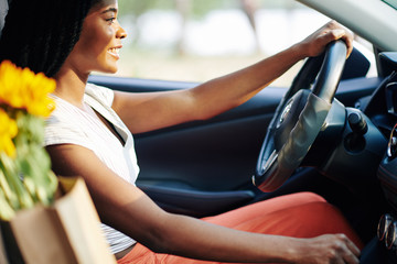Smiling yuong Black woman driving home from supermarket or shopping mall