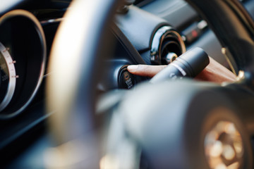 Close-up image of female driver pushing launch control button in modern car