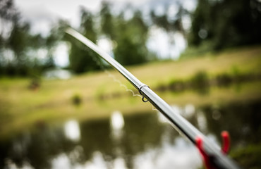 Fishing rod and a pond in background.