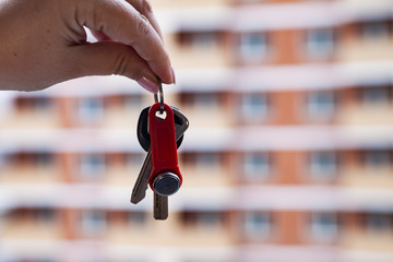 Keys in a hand on a background of an apartment building.
