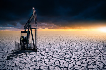 Oil rig in the desert on a background of a dramatic sky. Symbol of the crisis in the oil industry