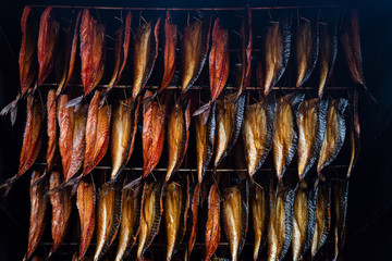 Smoking fish filets hanging side by side in a smoker. Cold smoked mackerel pieces for sale in fish...