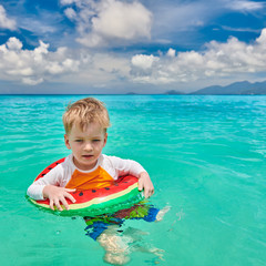 Toddler boy on beach swimming with inflatable ring