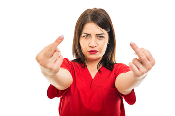 Portrait of beautiful doctor wearing scrubs using showing obscene gesture