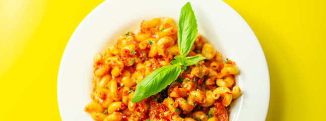 Cooked cellentani pasta with cooked chicken breast and peppers in a spicy tomato and jalapeno dressing