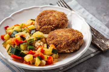 Minced beef cutlets served with and stewed vegetables.