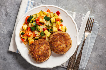 Minced beef cutlets served with and stewed vegetables.