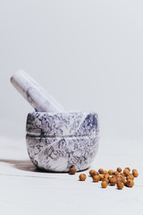 Stone white mortar and dried herbs, pepper, coriander ona a white wooden background table.