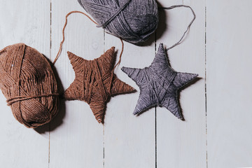 Ball of yarn. Two stars made from worsted lying on a white wooden background, decoration handmade...