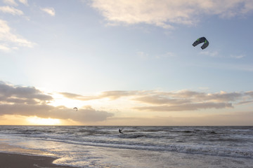 View of the north sea beach on a windy winter day at sunset, people, kitesurfing. Noordwijk, the Netherlands