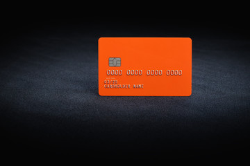 Orange credit card on dark textile background
