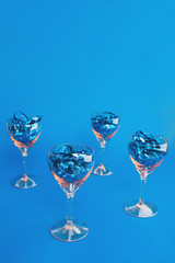 Glasses with confetti on blue background. Holiday concept. Flat lay, copy space, top view.
