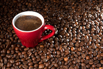 coffee in a red cup on a background of coffee beans