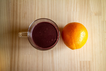 ガラスのマグカップのアサイードリンクとオレンジ１個 a glass cup of açaí drink and an orange 2