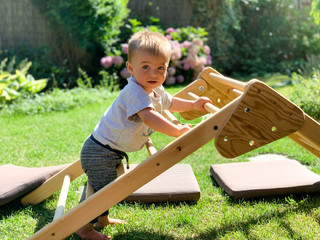 Baby learning to stand and climb on a wooden structure