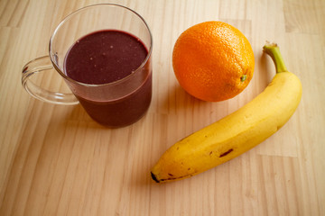 ガラスのマグカップのアサイードリンクとオレンジ１個とバナナ１本 a glass cup of açaí drink, a banana and an orange 5
