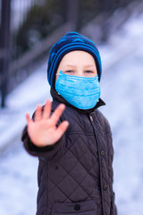 Fototapeta na wymiar Young little boy wearing medical face masks showing stop hand gesture for stop corona virus outbreak on the street during quarantine. Corona virus, covid -19, pandemic protection concept.