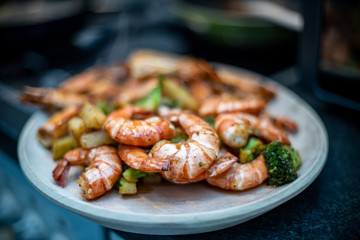 Wood plate with shrimp and broccolis over the table