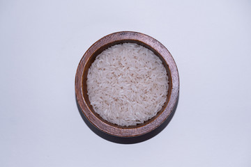 Rice isolated in a wooden bowl on white background. Top view.