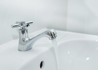 Close up water flowing faucet with on bathroom