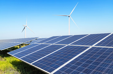 Rows array of polycrystalline silicon solar panels and wind turbines generating electricity in hybrid power plant systems station under blue sky is produce energy from natural 