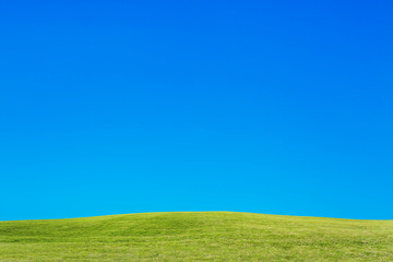 雲一つない青空と緑の丘。背景用素材