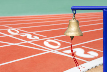 Close up golden bell final round the side of running track lane with text 2020 start to new year...