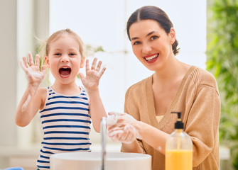 girl and her mother are washing hands