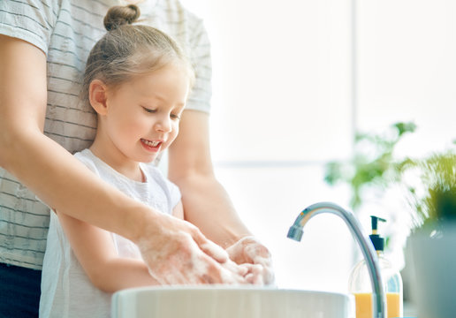 girl and her mother are washing hands