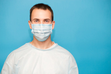 Portrait of sick patient man in protective medical mask against viruses and infections isolated on blue