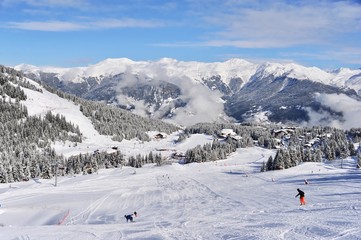 Naklejka na ściany i meble Ski resort by winter with skiing and snowboarding people on the slope 