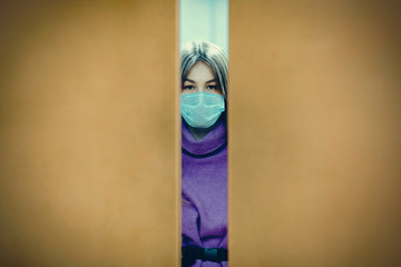 Young woman standing in closing elevator in medical mask. Coronavirus COVID-19 pandemic concept.