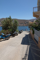 road to the sea along houses in the shade and motorbikes in the sun.Vertical orientation