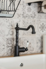 Cozy, bright Scandinavian-style kitchen. White, gray, black. Dishwashing sink, faucet, metal dishwasher, tile with patterns.