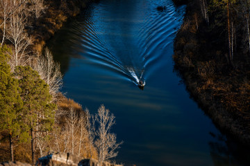 a motor boat sails along the river leaving a beautiful trail