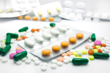 The concept of pills for treatment. Multi-colored white,  yellow, orange, green, pink tablets on a white isolate background . Copy space. 