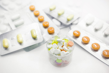 The concept of pills for treatment. Multi-colored pills in blisters on a white isolate. In a measuring glass in bulk, tablets of different colors. A serving of pills for today. Daily dose.