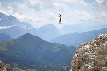 tightrope walker on a mountain with blue sky and clouds