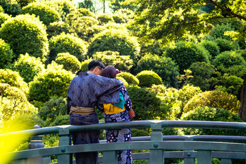 A young couple wearing kimonos cuddling on a bridge
