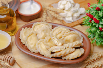 Dumplings on a wooden board with vegetables and cottage cheese