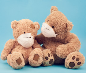 big brown teddy bears are sitting in medical masks on a blue background